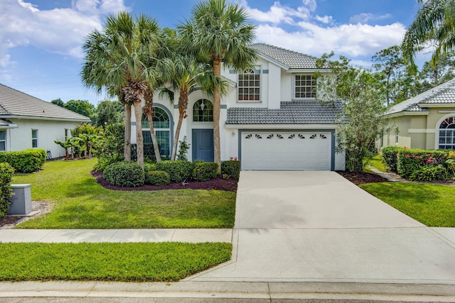 view of front of house featuring stucco siding, driveway, an attached garage, a front yard, and a tiled roof