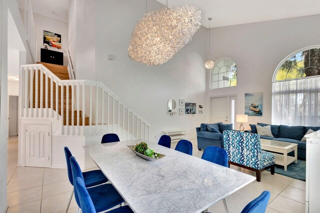 dining room featuring light tile patterned floors, stairway, a high ceiling, and a chandelier