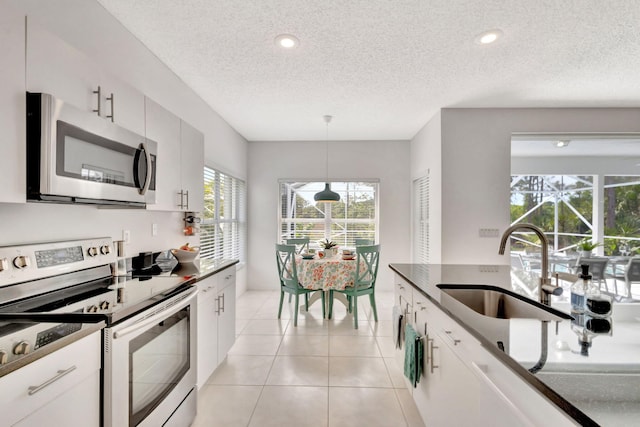 kitchen featuring a sink, stainless steel appliances, hanging light fixtures, and white cabinetry