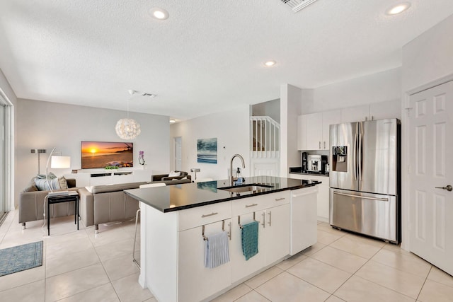 kitchen featuring a sink, dark countertops, white cabinetry, stainless steel fridge, and dishwasher