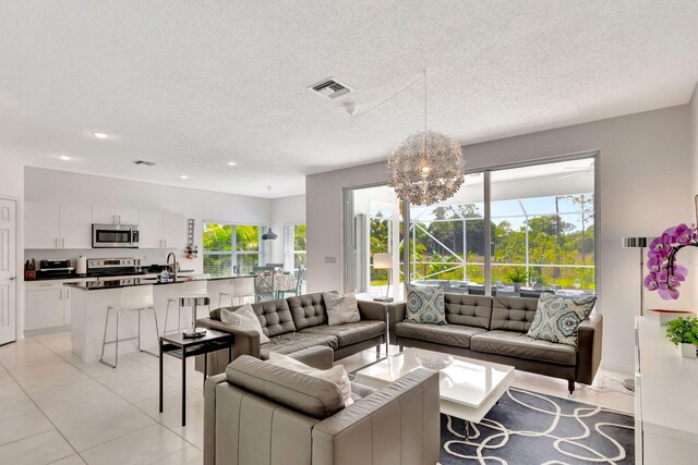 living area featuring light tile patterned floors, visible vents, plenty of natural light, and a chandelier