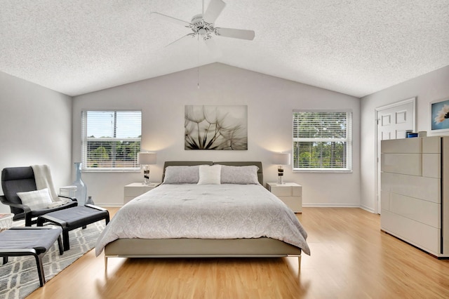 bedroom featuring vaulted ceiling, a ceiling fan, light wood-type flooring, and a textured ceiling