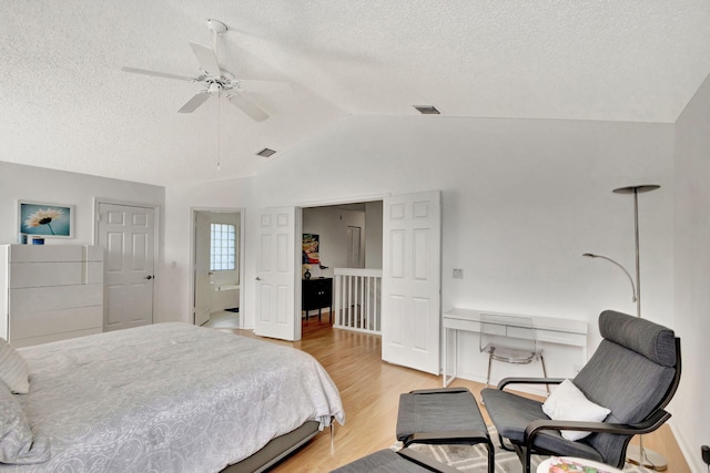 bedroom featuring visible vents, a textured ceiling, wood finished floors, and vaulted ceiling