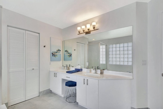 bathroom featuring a closet, double vanity, walk in shower, and a sink