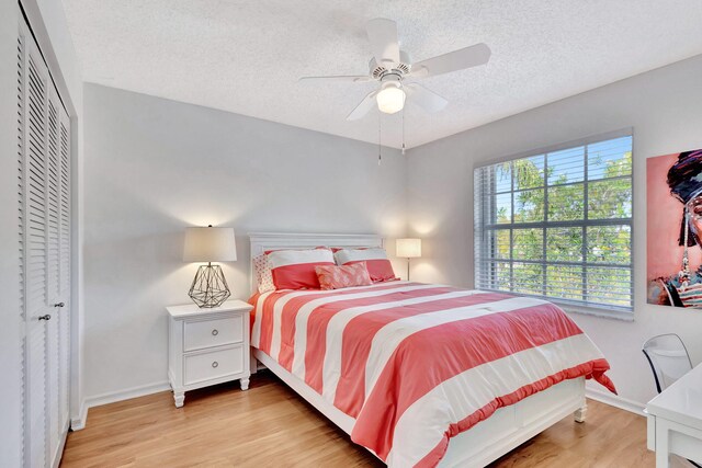 bedroom featuring wood finished floors, baseboards, ceiling fan, a closet, and a textured ceiling