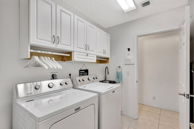 clothes washing area featuring visible vents, light tile patterned flooring, cabinet space, a sink, and washer and dryer