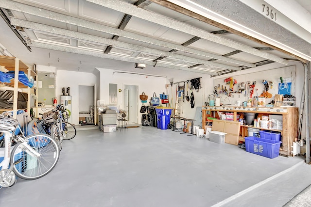 garage featuring electric panel, a workshop area, and water heater