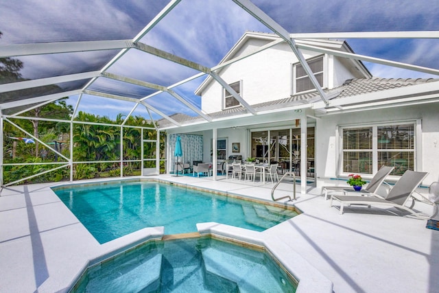 view of swimming pool featuring a patio area, glass enclosure, and a pool with connected hot tub