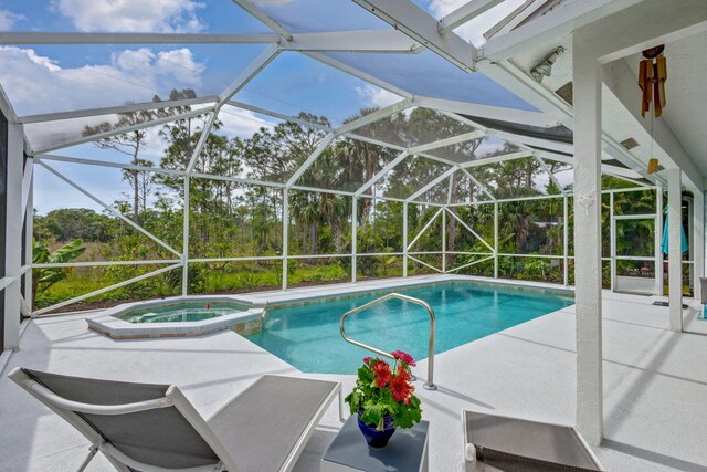 view of pool with a patio area, glass enclosure, and a pool with connected hot tub