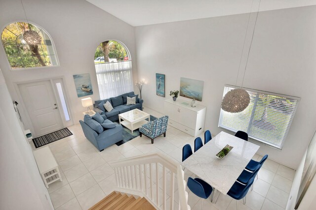 living area featuring tile patterned floors, high vaulted ceiling, and an inviting chandelier