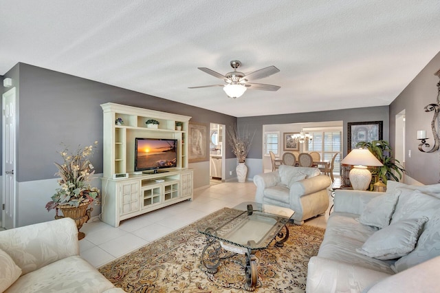 living room with light tile patterned floors, a textured ceiling, and ceiling fan with notable chandelier