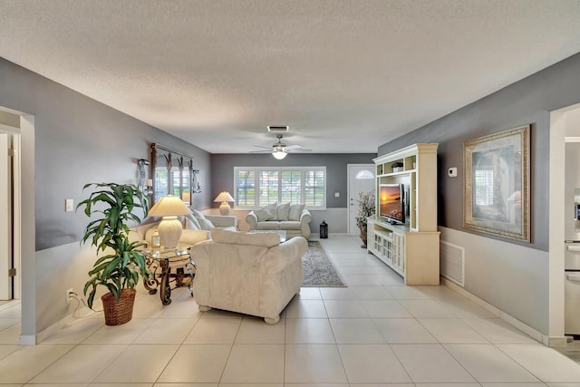 living room with a ceiling fan, visible vents, a textured ceiling, and light tile patterned floors