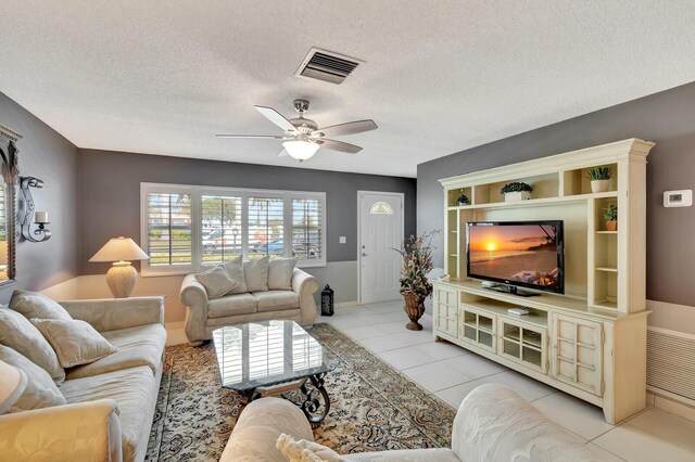 living room featuring light tile patterned floors, ceiling fan, a textured ceiling, and visible vents