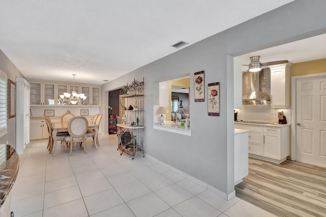 dining room with light wood-style floors, visible vents, baseboards, and ceiling fan with notable chandelier