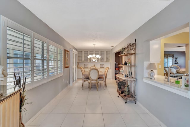 dining space featuring light tile patterned floors, baseboards, and a notable chandelier