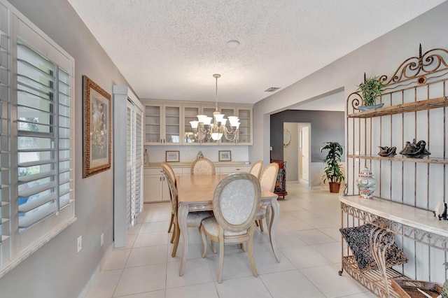 dining area with a chandelier, light tile patterned floors, a textured ceiling, and visible vents