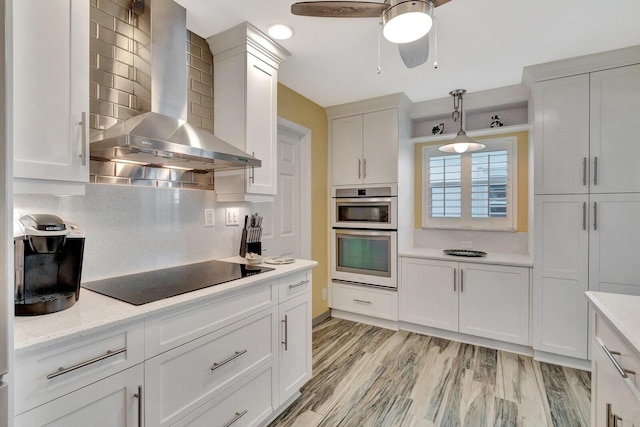 kitchen with wall chimney exhaust hood, black electric stovetop, backsplash, and white cabinetry