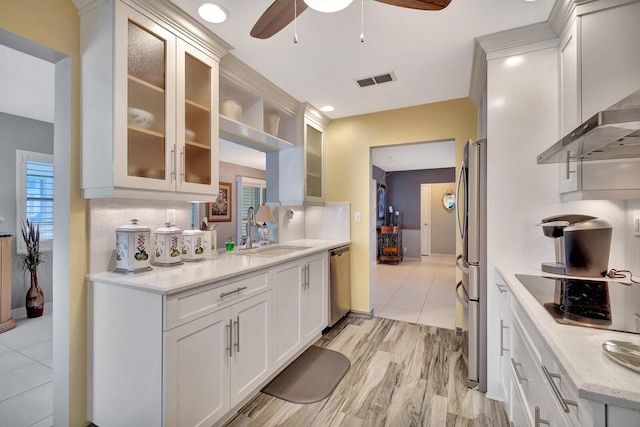 kitchen with visible vents, appliances with stainless steel finishes, white cabinetry, a sink, and wall chimney exhaust hood