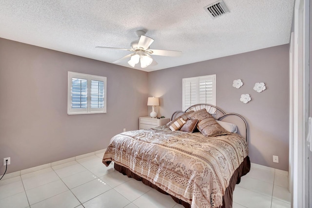 bedroom with a textured ceiling, visible vents, and a ceiling fan