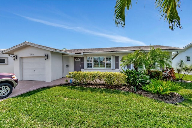 single story home featuring a garage, a front yard, and stucco siding