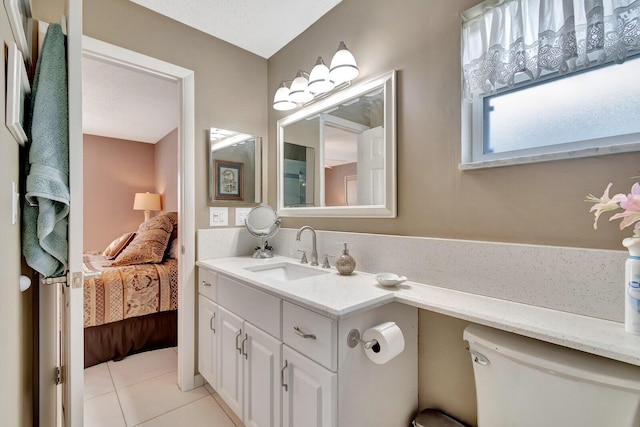 ensuite bathroom featuring tile patterned flooring, connected bathroom, vanity, and toilet