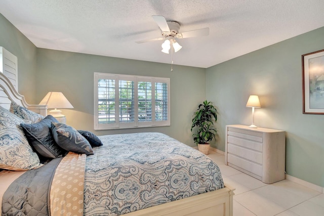 bedroom with light tile patterned floors, ceiling fan, baseboards, and a textured ceiling