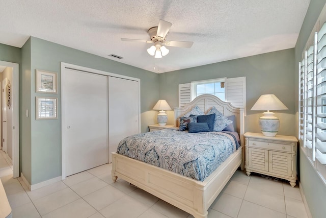 bedroom featuring visible vents, ceiling fan, a textured ceiling, a closet, and light tile patterned flooring