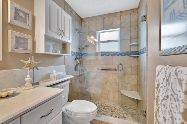 bathroom featuring a textured ceiling, a stall shower, vanity, and toilet