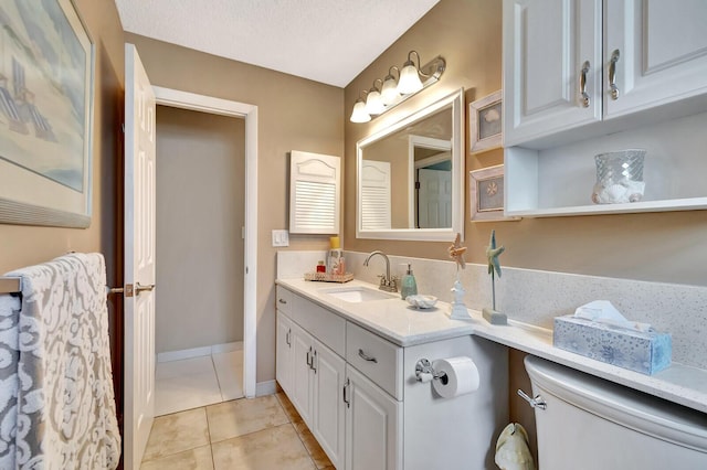 bathroom featuring toilet, vanity, a textured ceiling, tile patterned flooring, and baseboards