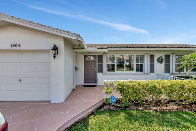 entrance to property featuring a garage and stucco siding