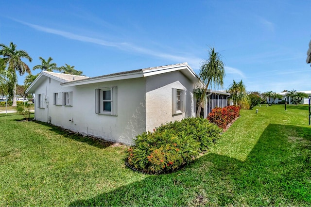 view of side of property featuring stucco siding and a yard