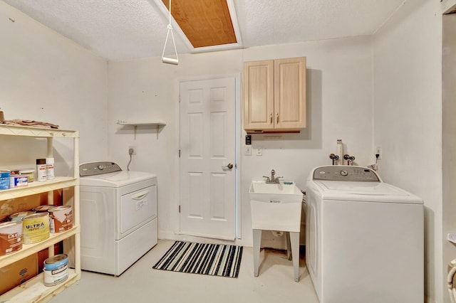 laundry area featuring a sink, cabinet space, separate washer and dryer, and a textured ceiling