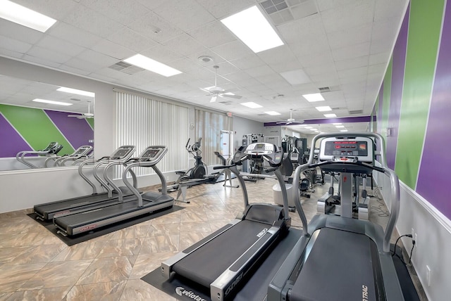 exercise room with ceiling fan, a drop ceiling, and visible vents