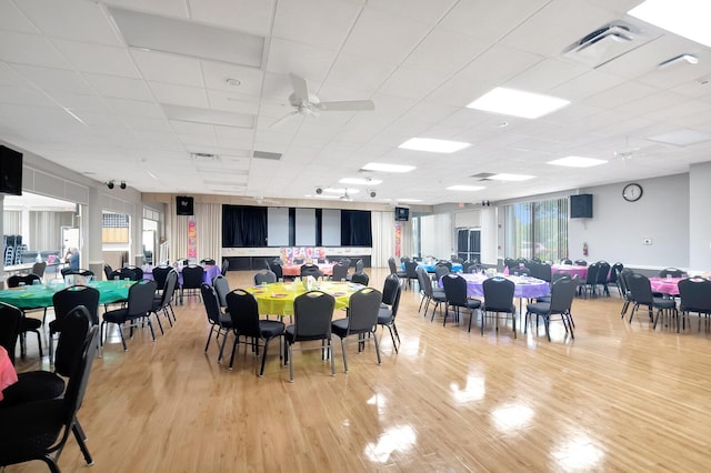 dining area with light wood-style floors, a ceiling fan, visible vents, and a drop ceiling