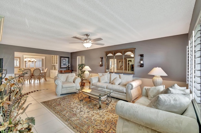 living area with ceiling fan with notable chandelier, a textured ceiling, and tile patterned floors