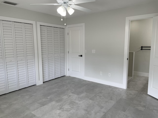 unfurnished bedroom with visible vents, two closets, baseboards, and a ceiling fan