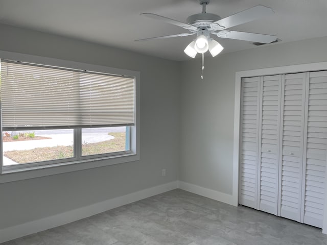 unfurnished bedroom with a closet, baseboards, and a ceiling fan