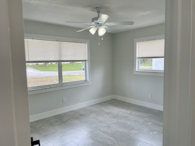 spare room featuring a ceiling fan and baseboards