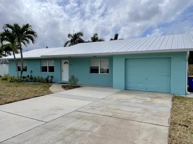 single story home featuring concrete driveway, metal roof, a garage, and stucco siding