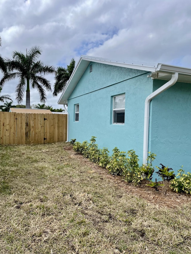 view of side of home with fence and stucco siding