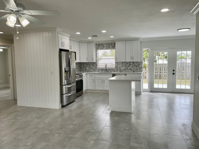 kitchen with a sink, stainless steel appliances, crown molding, light countertops, and decorative backsplash