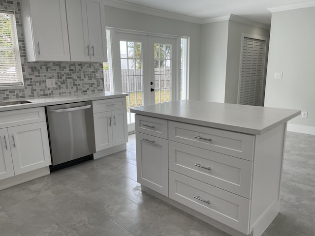 kitchen featuring tasteful backsplash, stainless steel dishwasher, white cabinets, crown molding, and light countertops