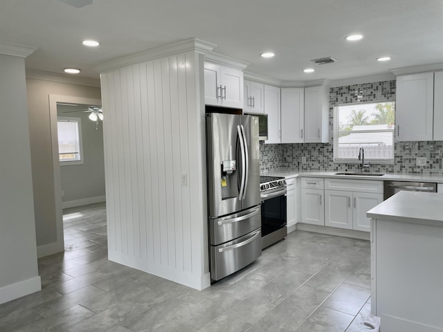 kitchen featuring backsplash, crown molding, light countertops, stainless steel appliances, and a sink