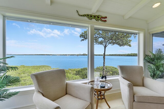 sunroom / solarium featuring a water view and vaulted ceiling with beams