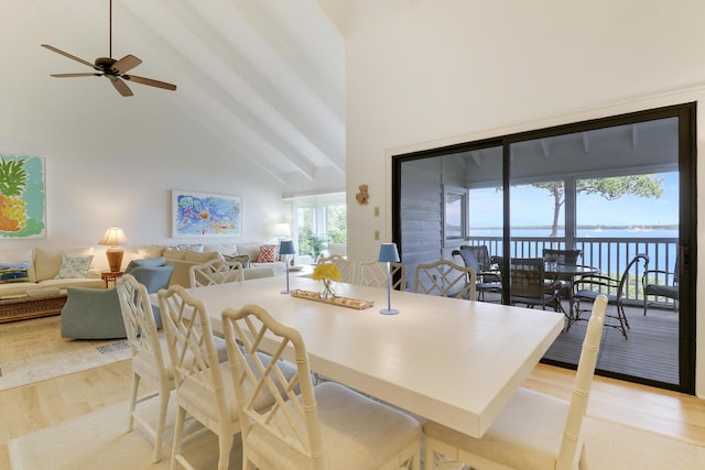 dining space featuring high vaulted ceiling, beamed ceiling, a water view, and light wood-style flooring