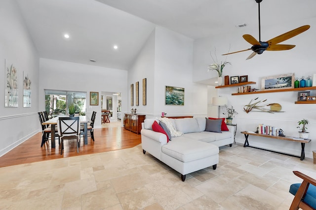 living room with recessed lighting, stone tile floors, visible vents, baseboards, and a towering ceiling