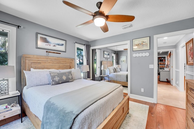 bedroom featuring baseboards, multiple windows, visible vents, and light wood-style floors