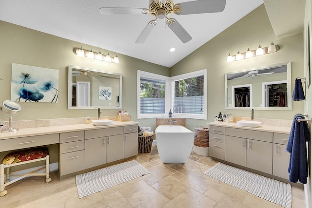 full bathroom featuring lofted ceiling, two vanities, a sink, and a freestanding bath