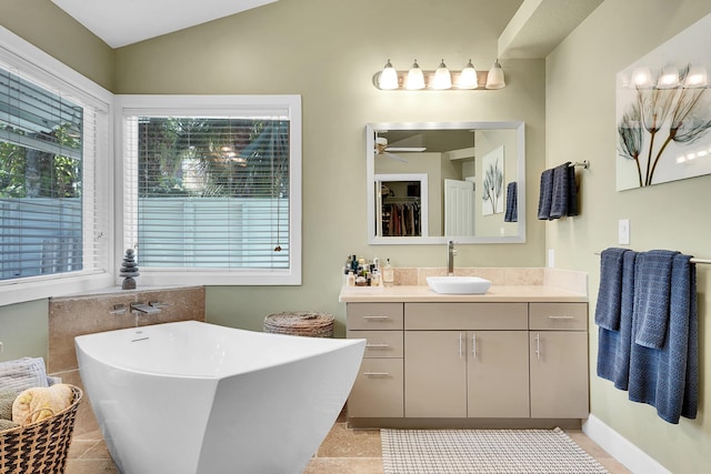 bathroom featuring a freestanding tub, vaulted ceiling, vanity, and ceiling fan