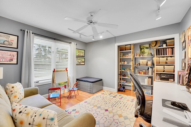 office space featuring ceiling fan, wood finished floors, rail lighting, and baseboards